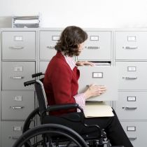 niepełnosprawna kobieta szuka czegoś w szafie z aktami